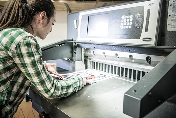 Tianna Blair shows how the massive paper cutter makes Fireball's production so effecient