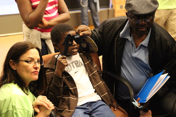 Child taking eye exam with help from Dad